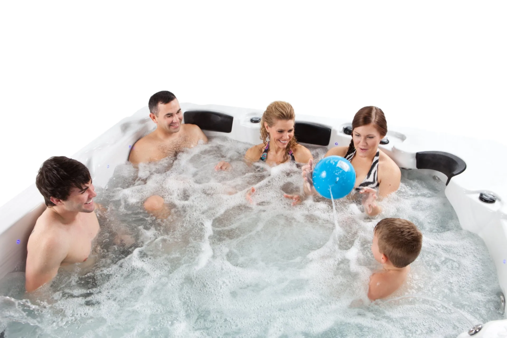 5 Family-Friendly Games to Play in Your Swim Spa 4 Pictured is a family of five sitting together in a swim spa. The swim spa jets are running and the family is playing catch with a blue ball.