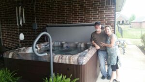 A man and a woman and standing next to their newly purchased hot tub.